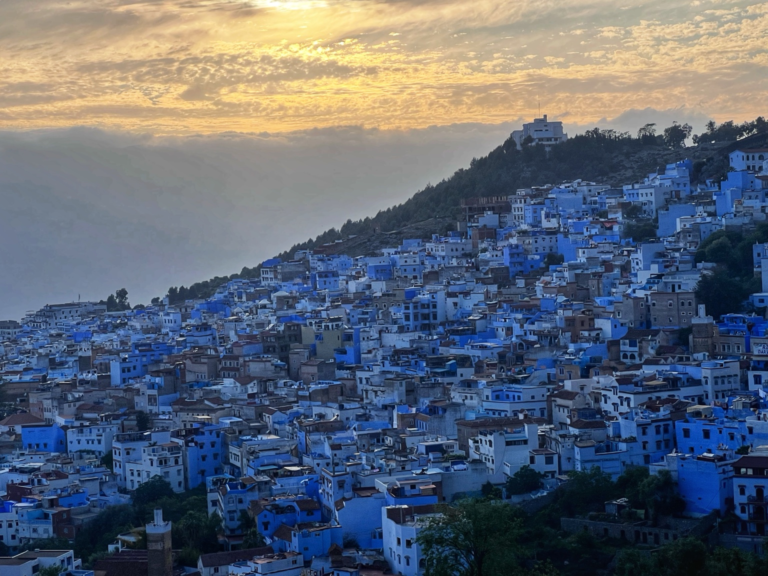 Blue buildings across a Moroccan hillside at sunset