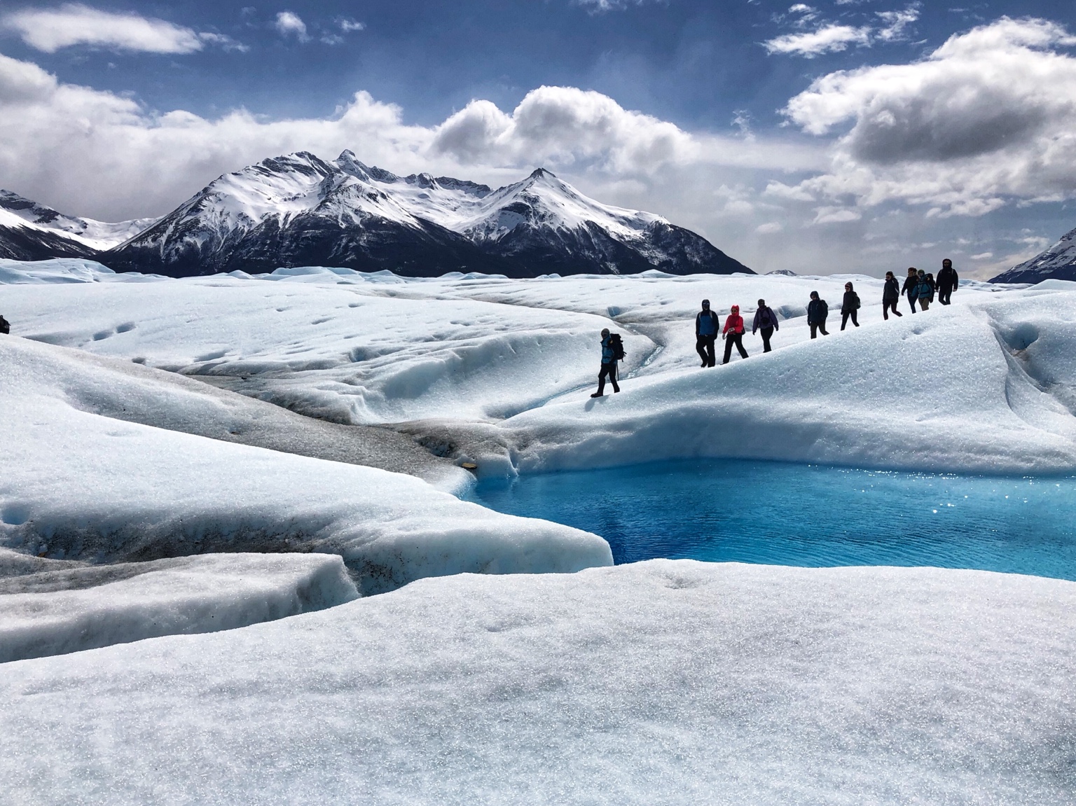Travelers walking beside blue ice at Perito Moreno Glacier, Argentina